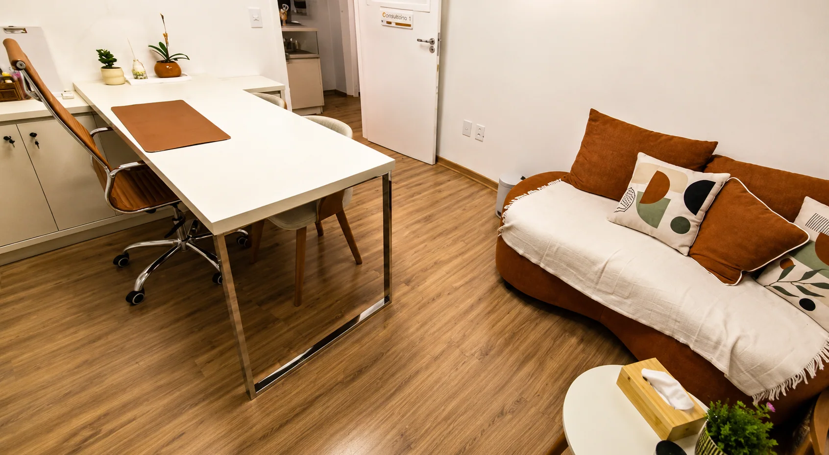 Consultório 03 do Instituto Axon Savant com mesa de atendimento, sofá e ambiente amplo.